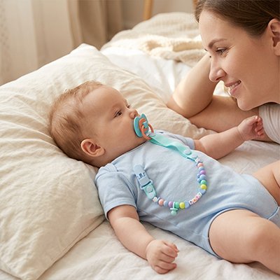 Attache tetine bebe sur le lit avec maman