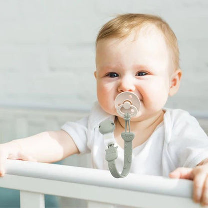 Attache tetine universel et mignon bebe debout dans son berceau
